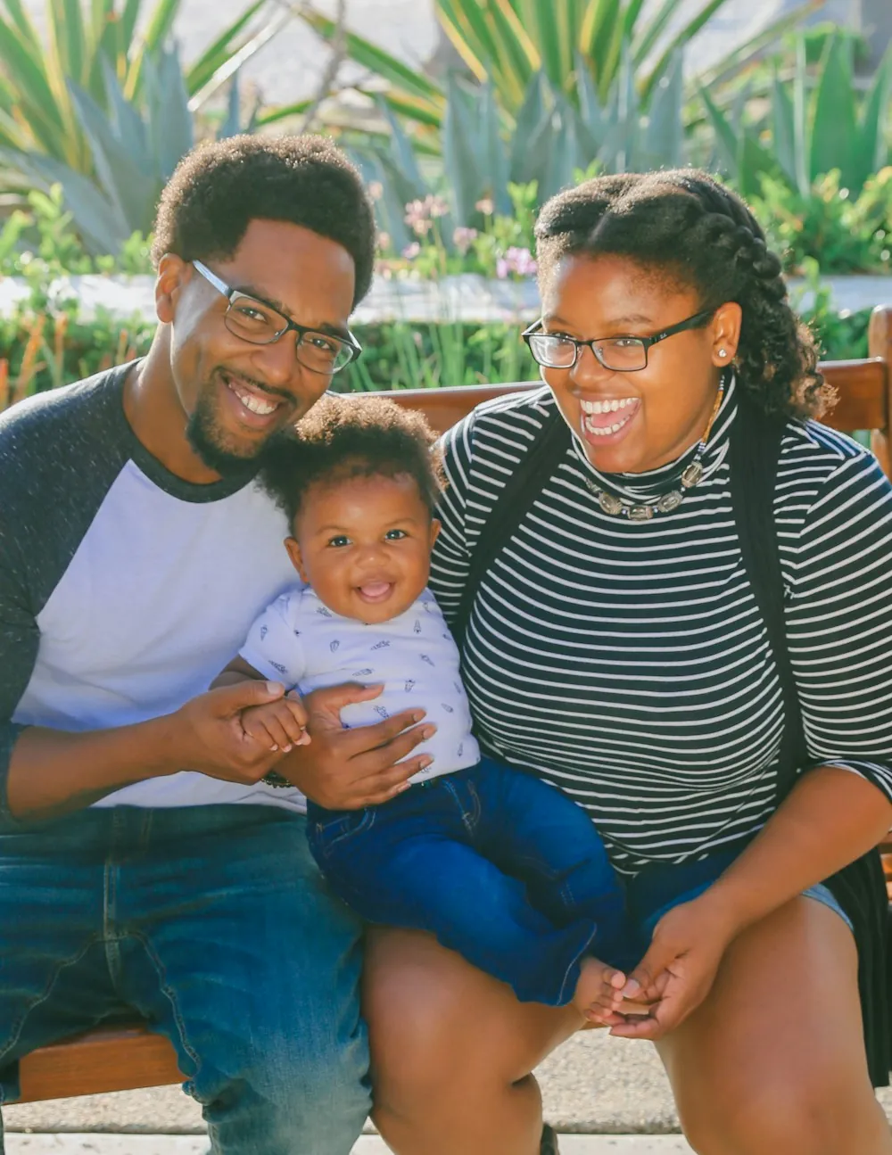 A father and mother smiling at home with their baby