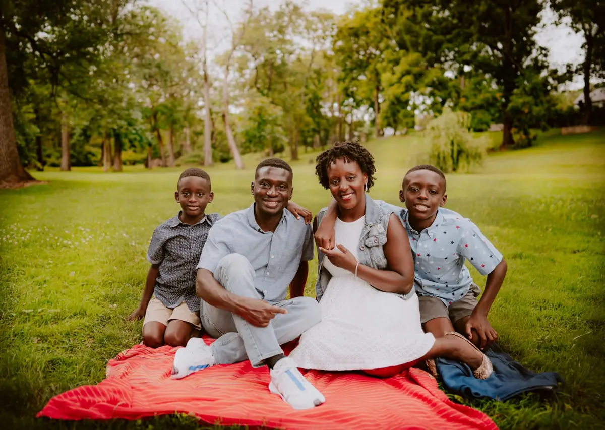 A father, mother and three children smiling together on a picnic blanket in a park